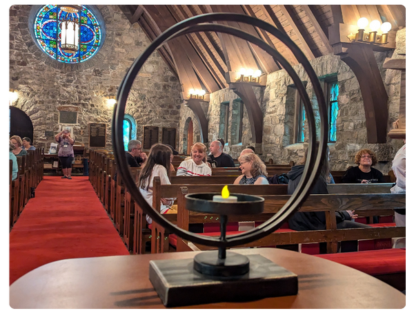 metal two ring chalice lit in stone chapel with multi-generational congregation