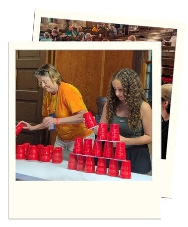 elder camper and youth camper compete in a cup stacking game