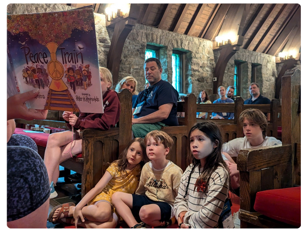 children sit on the floor of a stone church listening to a book