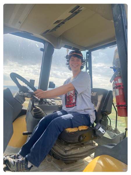 imogen parker drives a tractor with cloud skies behind